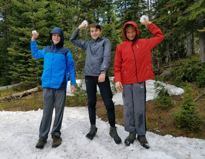 teenagers throwing snowballs in summer in yellowstone national park